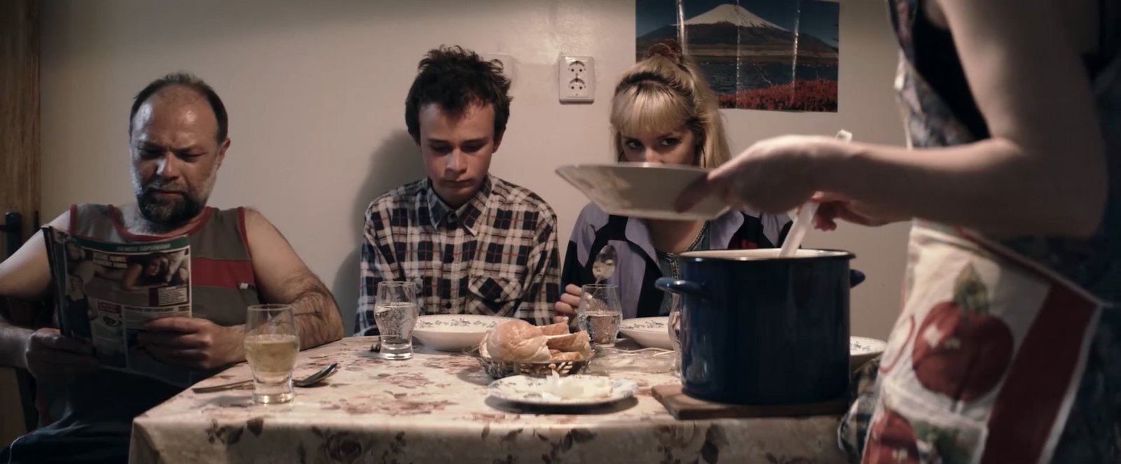 A family gathered around a dining table in Table of Silence