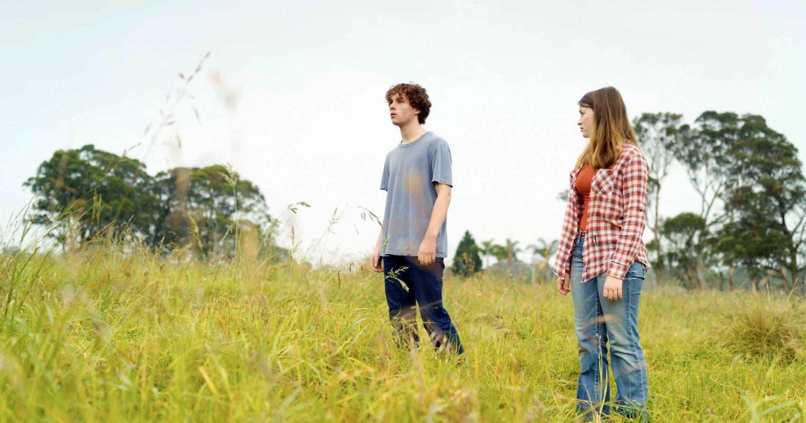 Two young people face one another in a field in The Dam